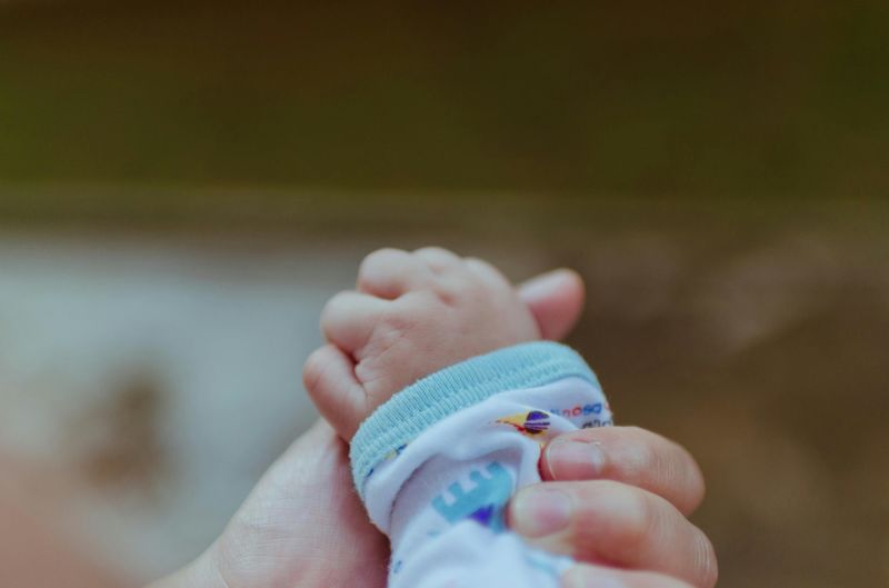 A newborn baby's hand gripping a parent's finger